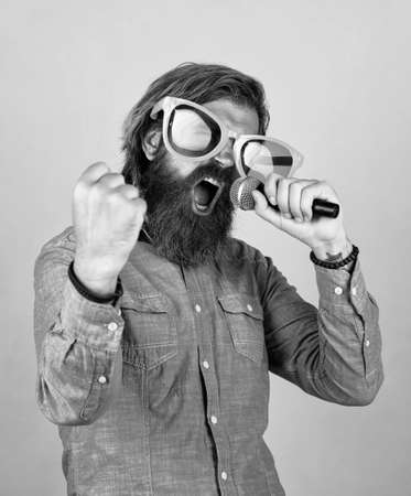 Modern music. hipster man with beard wearing glasses. music concept. have a happy holiday. have fun on party. male singer singing song in microphone. celebrate the anniversary. party goerの写真素材