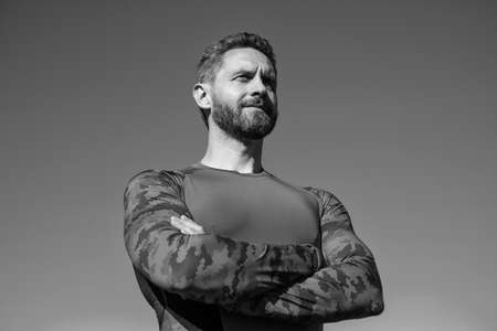 confident sportsman in sportswear on sky background, fitness coach