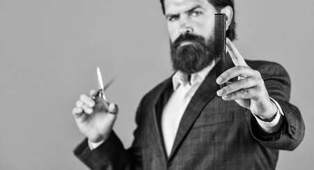 his perfect style. Mature hipster with beard. brutal caucasian hipster with moustache. Male barber care. Bearded man hold hair brush and scissors. Confident and handsome brutal man. facial careの写真素材