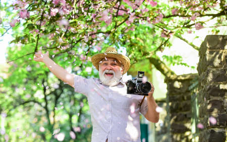 hobby at retirement. tourism and holiday. traveler camera man under sakura bloom garden. travel concept. male photographer enjoy blossom. travel and walking in cherry park. Enjoying spring holidayの写真素材