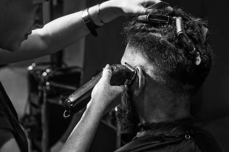 beauty and fashion. hair and beard styling. brutal guy with barbershop professional master use electric shaver. hipster. male barber care. bearded man at hairdresser chair in salon. Beauty Conceptの写真素材