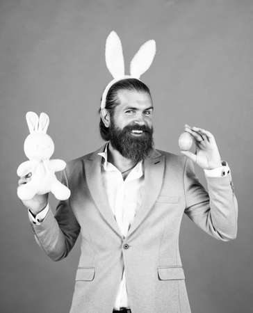 decoration easter egg. male funny egg hunt. bearded man in formalwear and hare ears. elegant businessman wear elegant apparel for spring holiday. happy easter. true gentleman with bunny earsの写真素材