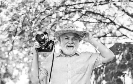 Spring time. senior bearded man photographing pink blossom. professional photographer designer. happy retirement. man tourist use camera take photo of cherry blossom. sakura in full bloom photographyの写真素材