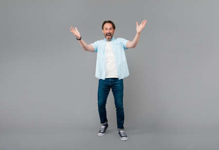 Happy old man in casual gesticulate with open arms grey background, welcoming