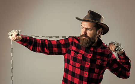 Cowboy man with beard and mustache pull steel chain, routine at ranchの写真素材