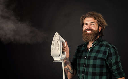 mature brutal hipster with steaming iron in shirt, ironingの写真素材