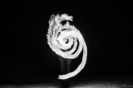 Fire artist perform fiery circular arcs pattern at night in dark, fibonacci spiral