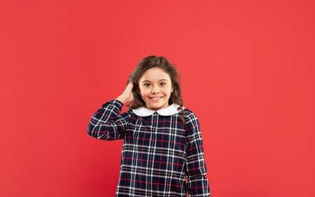 cheerful child with long curly hair on red background, hairstyling
