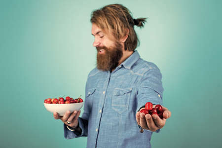 try this. organic fruits. confident farmer with fresh fruits. bearded man holding ripe cherries....