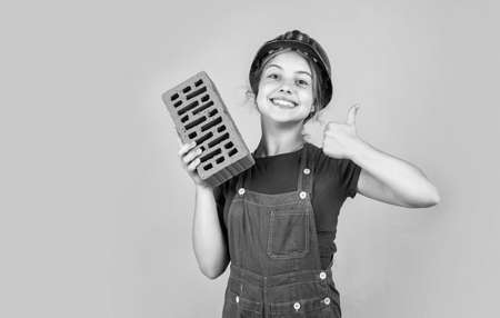 teen girl builder in protective helmet use brick, build future