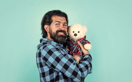 male holding birthday or valentines day present. bearded man in checkered shirt hold teddy bear. casual guy express love emotions. happy hipster with moustache play toyの写真素材