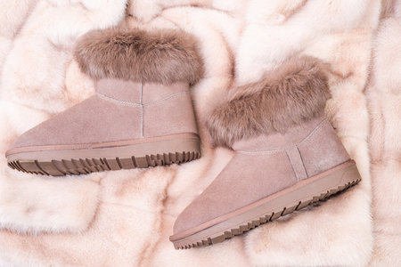 pair of fashionable suede ugg boots. ankle boots on blue background. shoe store.の写真素材