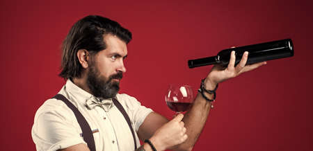brutal bartender man pouring wine in glass from bottle. Only truly connoisseur can feel fragranceの写真素材