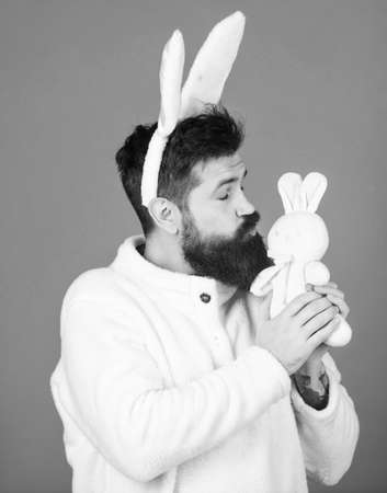 My cute bunny. Bearded man in easter rabbit costume holding hare toy. Happy man with rabbit ears kissing bunny toy. Symbolizing spring, new life and fertility. Spring holiday celebrationの写真素材