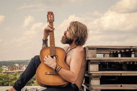 handsome bearded guy with stylish hair playing acoustic guitar, string instrument