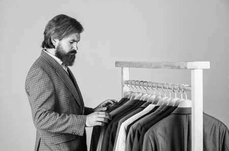 Businessman handsome guy in clothes shop choosing garments, good assortment conceptの写真素材