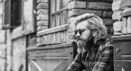 Bearded man checkered shirt. Hipster dyed hair and beard. Hairdresser and barbershop. Brutal male with blond hair irish architecture background. Man casual fashion. Hipster in sunglasses. Cool guyの写真素材