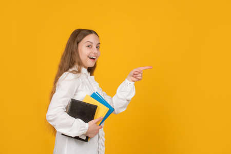 amazed child with book point finger on copy space. back to school. childhood education.