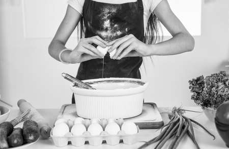 kid cooking food in kitchen. choosing a career. little helper with egg. culinary and cuisine. happy childhood. child wear cook uniform. chef girl in hat and apronの写真素材