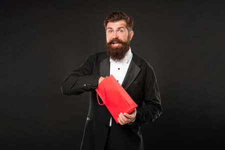 surprised man in tuxedo bow tie formalwear on black background with shopping bag. birthdayの写真素材