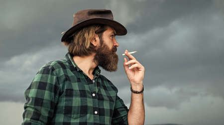 unhealthy way of life. smoking concept. mature brutal hipster in cowboy hat and checkered shirt....