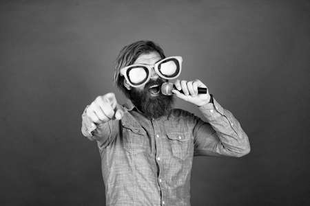 mature bearded guy has long hair wearing party glasses and singing in mic, vocalの写真素材
