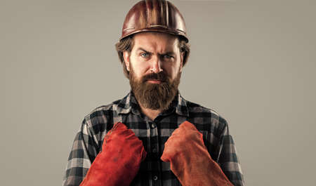 brutal man builder in uniform and helmet with gloves, worker