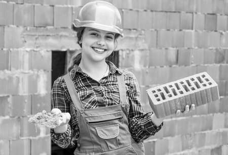 happy kid engineer with brick in hard hat, buildingの写真素材