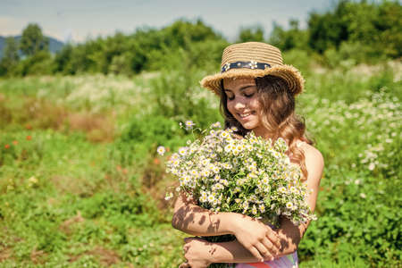 Harvest fresh herbs. Little girl collecting chamomile flowers in field, carefree and happyの写真素材