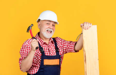 happy senior man woodworker in helmet on yellow backgroundの写真素材
