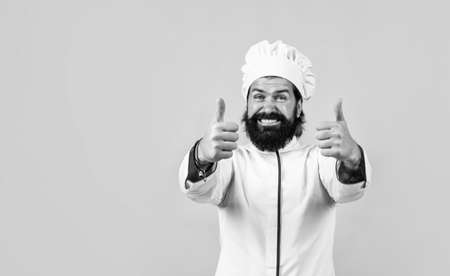 happy male chef in hat with beard and moustache on blue background, thumbs up for success and perfectionの写真素材