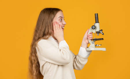 amazed kid with microscope on yellow backgroundの写真素材