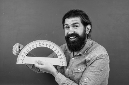 studying the measurement. formal education. male student at mathematics school lesson. pass the math exam. learning the subject. happy man with beard using protractorの写真素材