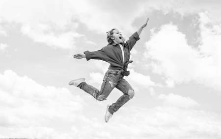 Add some action to your life. happy kid on sky background. cheerful retro girl. child having fun. happy childhood. enjoy good weather forecast. girl wearing casual style clothes. spring fashion wearの写真素材