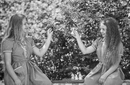 two teen girls play chess in retro dress outdoor, childhoodの写真素材
