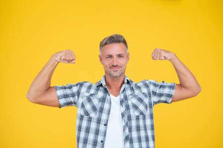 strong mature man with grizzle hair on yellow backgroundの写真素材
