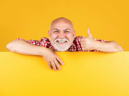 cheerful senior man with copy space on blank banner. advertising. thumb upの写真素材