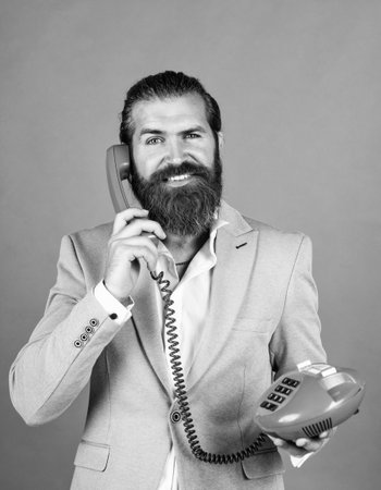 happy man with retro phone. brutal bearded man hold vintage telephone. concept of technology in modern life. communication. idea of conversation. man speak on phoneの写真素材