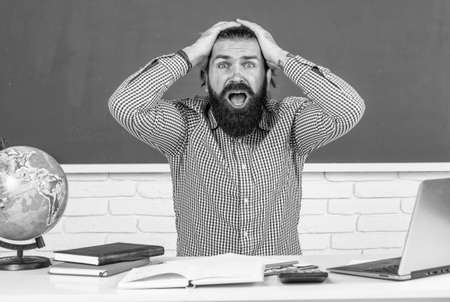 male student sit in school classroom while hard lesson. pass the exam. learning is hard. stressed hipster teacher. overworked man with beard having stress. troubles in studying. formal educationの写真素材