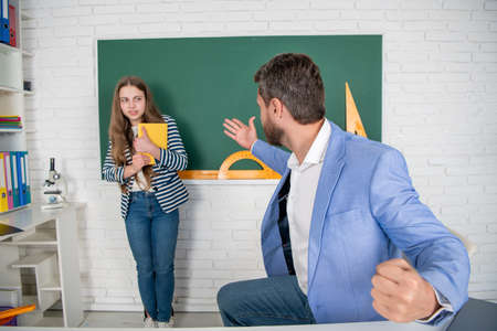 angry teacher shouting at child at blackboard. aggression