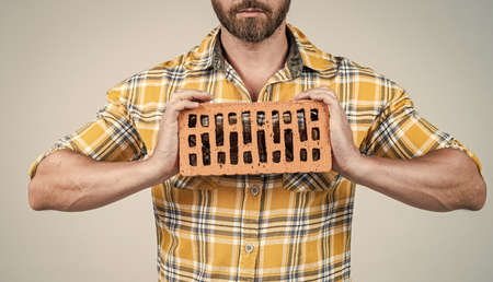 cropped man manual worker in checkered shirt with brick, bricklayerの写真素材