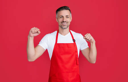 happy mature man waiter in apron on red backgroundの写真素材