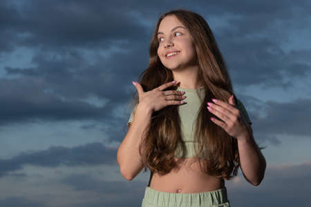 smiling teen girl with long wavy hair on sky backgroundの写真素材