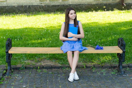 cheerful girl relax with book on park bench, copy spaceの写真素材