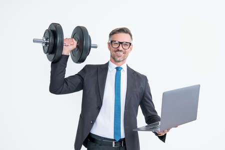 glad businessman in suit hold heavy dumbbell and laptop isolated on white backgroundの写真素材
