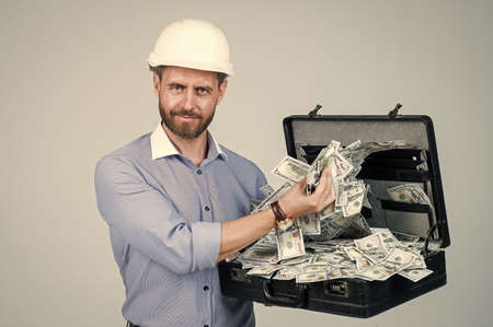 handsome smiling bearded businessman in helmet hold money case, financialの写真素材