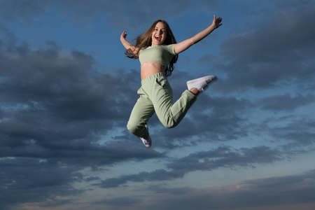 happy teen girl jumping high on sky backgroundの写真素材