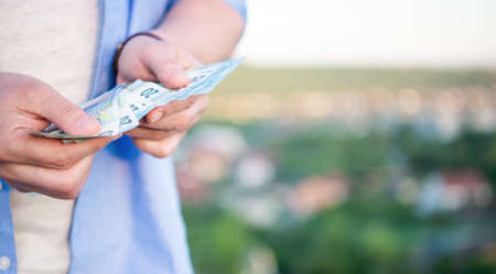 Guy crop view counting cash money banknotes blur outdoors, copy spaceの写真素材