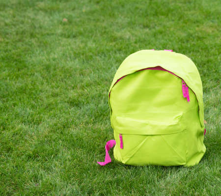 Green school backpack schoolbag bag standing on grass background, copy spaceの写真素材