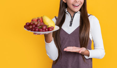 surprised child hold fresh fruit on yellow background